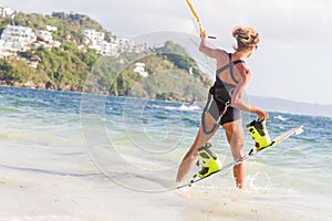 A young woman kite-surfer ready for kite surfing rides in blue s