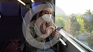 Young woman with KN95 FFP2 face mask using smart phone app. Train passenger with protective mask traveling sitting