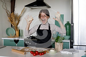 Young woman kneading the dough for italian pizza in the kitchen at home interior, fooling around