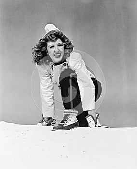 Young woman kneeling in snow and smiling