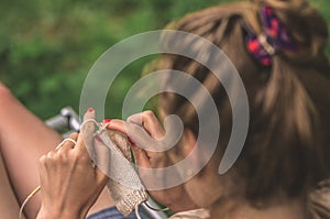 Young woman knits out of wool outdoors