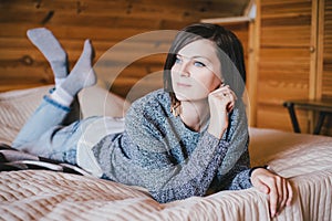 Young woman in a knitted sweater relaxing in a wooden countryhouse