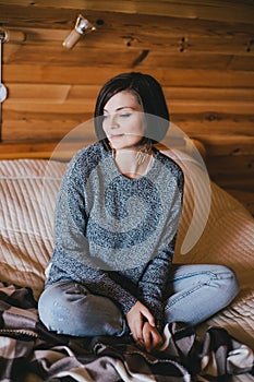 Young woman in a knitted sweater relaxing in a wooden countryhouse