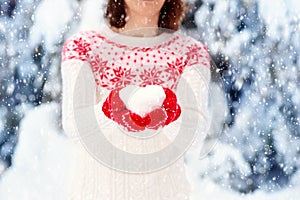 Young woman in knitted sweater with snow heart