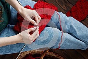 Young woman knitting red muffler at home in leisure time, fancywork and needlework concept