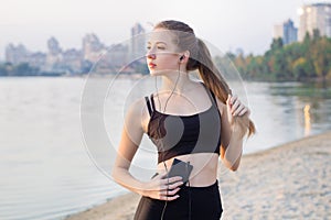Young woman at lake listening to music on cell phone