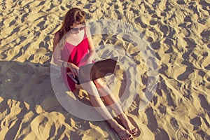 Young woman with laptop computer on the beach. Downshifting and