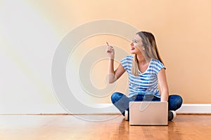 Young woman with a laptop computer pointing something