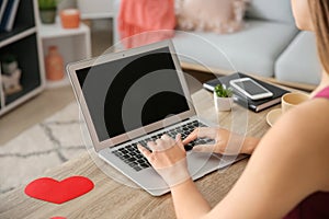Young woman with laptop having online dating at home