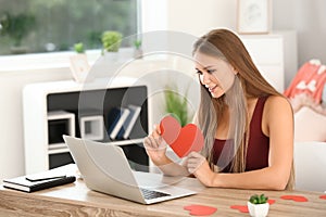 Young woman with laptop having online dating at home