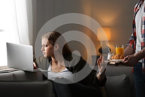 Young woman with laptop ignoring her boyfriend. Loneliness concept