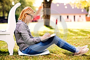 Young woman with a laptop studying outdoors.