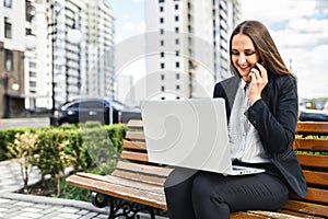 A young woman with laptop is talking on the phone