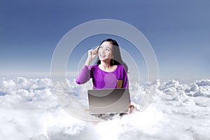 Young woman with laptop under blue sky