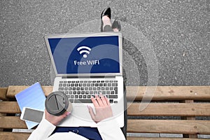 Young woman with laptop using free Wi-Fi outdoors