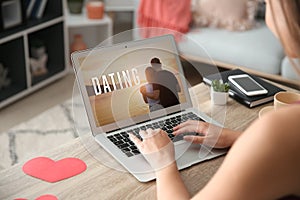 Young woman with laptop using website for online dating at home