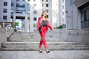 Young woman with laptop walking outdoors in business district