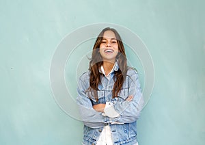 Young woman laughing with arms crossed in relaxed pose against blue background