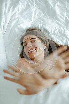 Young woman laughing lying in bed