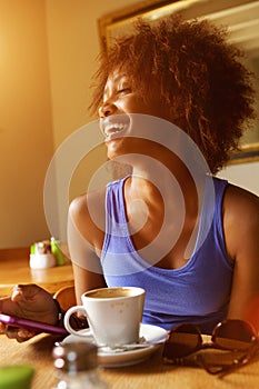 Young woman laughing with mobile phone at cafe