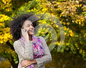 Young woman laughing outdoors with mobile phone