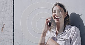 Young woman laughing while talking on the phone with a relative in the city. Female looking cheerful while having a