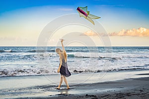 A young woman launches a kite on the beach. Dream, aspirations, future plans
