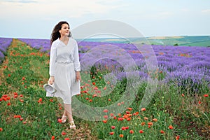 Young woman is in the lavender field, beautiful summer landscape with red poppy flowers