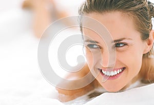 Young woman laying in bathtub and looking on copy space