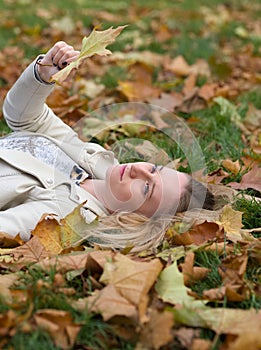 Young Woman Laying in the Grass in Autumn Park