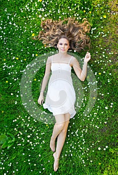 A young woman laying on the grass in a white dress