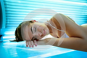 Young woman laying on solarium bed