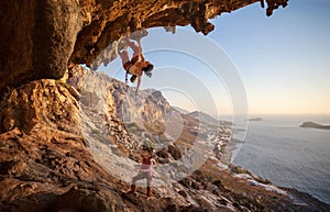 Young woman lead climbing along a roof in cave