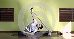 A young woman leading a healthy lifestyle, training with a fitness belt, doing stretching