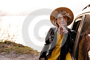 Young Woman Lean against Car at Riverside Portrait