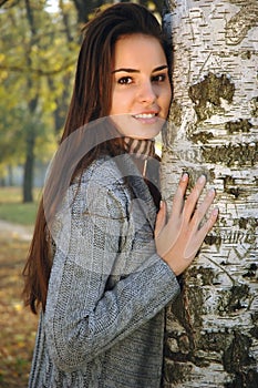 Young woman leaned on a birch
