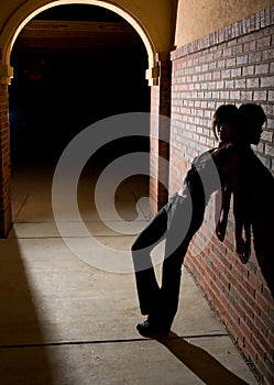 Young Woman Leaning Against Brick Wall at Night