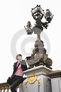 Young Woman Leaning On Ornate Streetlight