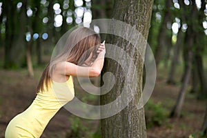 Young woman leaning to tree trunk in summer forest