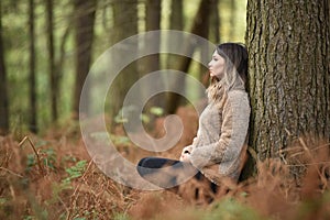 Young woman leaning on a tree in a lush forest