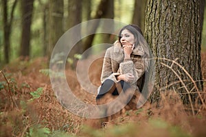 Young woman leaning on a tree in a lush forest