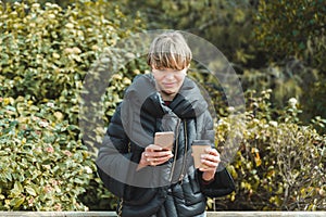 young woman leaning on wooden fence and using her cell phone