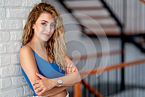 Young woman leans back to the wall and looking to a point wiyh a smily face.