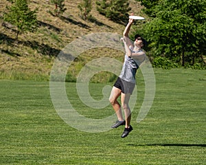 Young woman leaps for flying disc