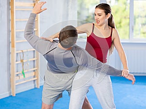 Young woman learning to do power grab on an opponent neck during self-defense training at gym