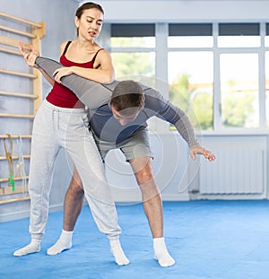 Young woman learns to do painful grip on arm of an attacking man during self defense training