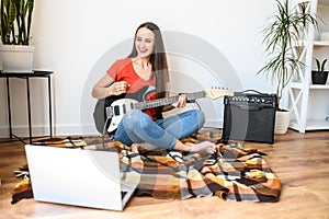 Young woman learns to play the electric guitar
