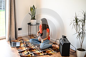 Young woman learns to play the electric guitar