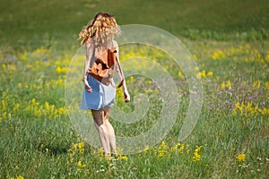 Young woman with a leather backpack in a summer field