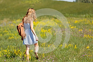 Young woman with a leather backpack in a summer field